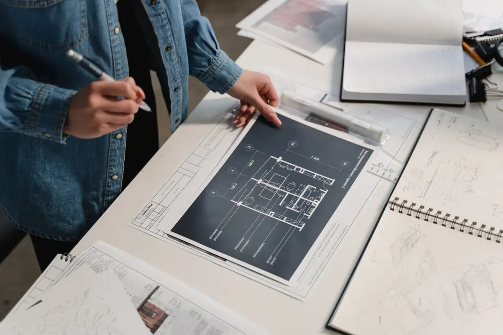 Two people marking up an architectural drawing across a table