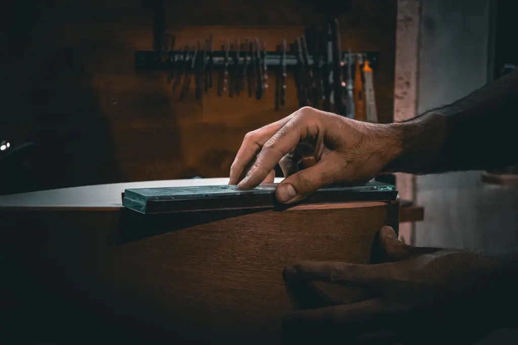 Hands working a plane across a machined component at the bench