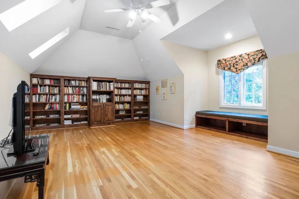 Library room with full height shelving and a window seat